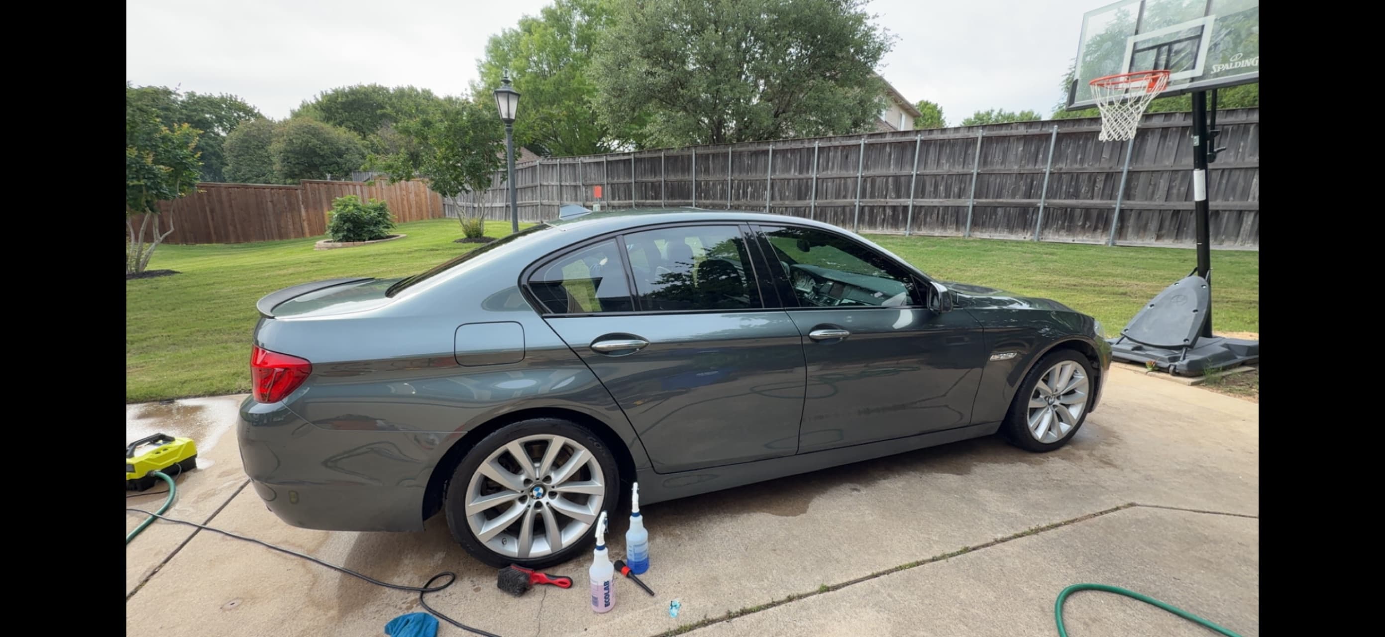 Dark gray BMW 5 Series freshly washed in the driveway